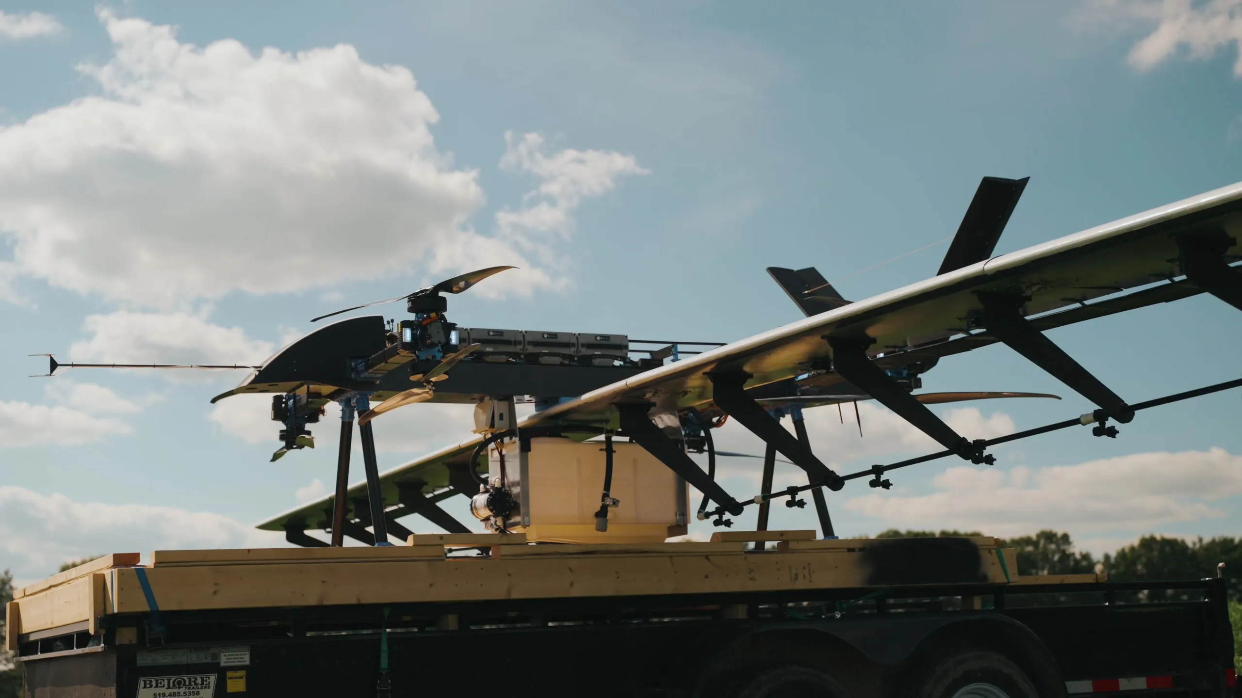 The U9 Spray loaded on a flatbed trailer with its wings extended, against a blue sky.